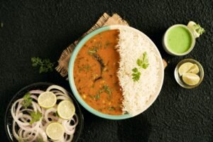 Top view of a traditional Indian meal with rice, curry, and fresh garnishes, perfect for lunch or dinner.