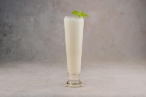 A chilled glass of lassi garnished with fresh mint leaves, perfect for a refreshing treat.